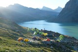 Fototapeta  - Colorful tents on bank of Lake Ala-Köl (Ala-kol, Ala-kul) in Tien Shan mountains in west of Kyrgyzstan, Asia. Cyan color of lake under steep mountaines. Touristic destination for trekking.