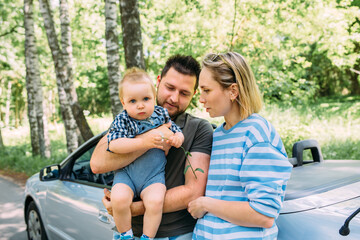 Mom, dad and little son in a convertible car. Summer family road trip to nature