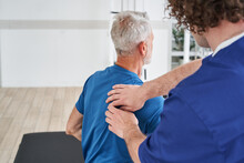 Manual Therapist Massaging Shoulder Blades Of Elderly Male During The Treatment