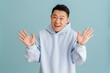 © Drobot Dean - Young asian man wearing hoodie gesturing and laughing at camera