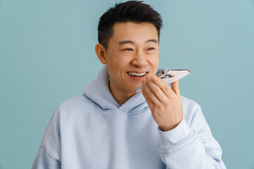 Wall Mural - Young asian man smiling while talking on mobile phone