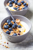 Fototapeta Mapy - Breakfast yogurt bowl with granola, blueberries and maple syrup, gray background.