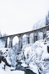  Mountain landscape with Sainte Marie bridge covered with snow in Les Houches, Chamonix valley, Eastern France. Viaduct bridge built to carry a railway over water.
