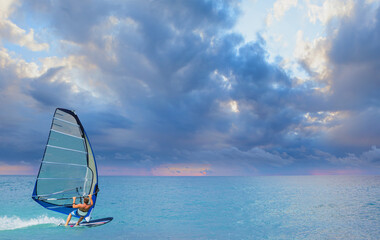 Beautiful stormy cloudy sky with Windsurfer Surfing The Wind On Waves