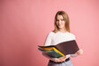© Julia Jones - A cute student girl with a set of folders for documents stands on a pink background