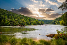 A Gorgeous Summer Landscape Along The Chattahoochee River With Flowing Water Surrounded By Lush Green Trees, Grass And Plants With Powerful Clouds At Sunset In Atlanta Georgia USA