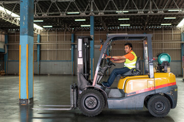 Asian male driver driving forklift to shipping delivery product in the warehouse distribution. import export logistic career, worker working at industrial factory.