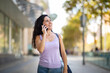 © mimagephotos - Smiling woman talking on mobile phone in city