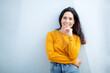 © mimagephotos - Beautiful woman posing with hand on chin against exterior wall