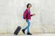 © mimagephotos - Happy man looking up while walking with luggage and mobile phone in city