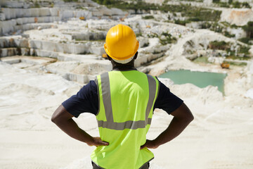 Aufkleber - Rear view of young foreman or engineer in reflective vest and safety helmet standing on territory of vast marble quarry