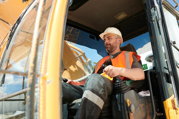 Aufkleber - Male builder or driver of construction machine in workwear and hardhat operating caterpillar truck while sitting in cab during work