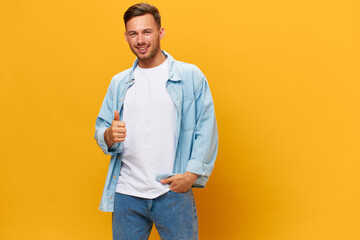 Wall Mural - Smiling joyful tanned handsome man in blue basic t-shirt show thumb up gesture Like posing isolated on orange yellow studio background. Copy space Banner Mockup. People emotions Lifestyle concept