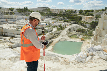Aufkleber - Side view of mature engineer or surveyor adjusting theodolite before measuring territory of marble quarry on summer day