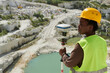 © pressmaster - Young serious African American female engineer or surveyor with theodolite standing on territory of vast marble quarry