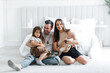 © halcon1 - Portrait of happy young parents and their little children in the bedroom. Dad mom their little daughter and newborn son. Happy young family having fun with each other