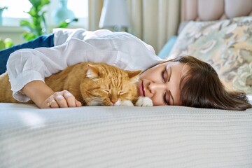 Wall Mural - Middle aged woman sleeping with big ginger cat on bed