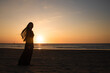© Milou Dirks - silhouette of a woman in long black dress on the beach at sunset