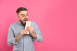 Young man eating delicious shawarma on pink background, space for text