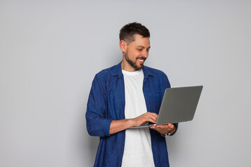 Smiling man with laptop on light grey background
