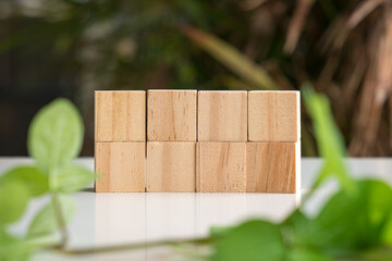 Eight blank wooden block cubes in two rows. On nature and green leaf background. Free text and template.