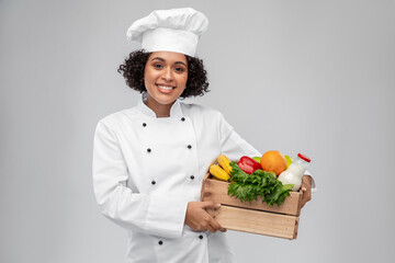 cooking, culinary and people concept - happy smiling female chef in toque holding food in wooden box over grey background