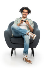 technology, people and leisure concept - happy smiling young man in glasses with gamepad sitting in chair and playing video game over white background