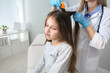 © New Africa - Doctor using nit comb on girl's hair in clinic. Anti lice treatment