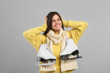 Wall Mural - Happy woman with ice skates on grey background