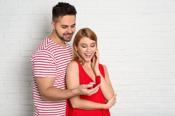 Sticker - Man with engagement ring making marriage proposal to girlfriend near white brick wall. Space for text