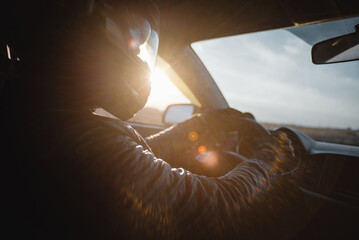 Rally car driver sitting by the steering wheel in the sunset rays concept.