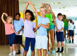 © JackF - Group of happy cheerful positive children practicing vigorous jive movements in dance class with female coach
