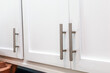 A close up of white shaker soft close cabinets with silver thin modern bar pulls