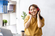 © David - Photo of attractive freelance Business asian woman 30s wearing headphones holding laptop and smartphone while sitting on desk in workplace,