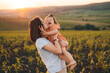 © Strelciuc - Young mother kissing her baby daughter in the green cornfield on summer day at sunset. Motherhood child care concept. Summer relaxation concept. Summer nature.