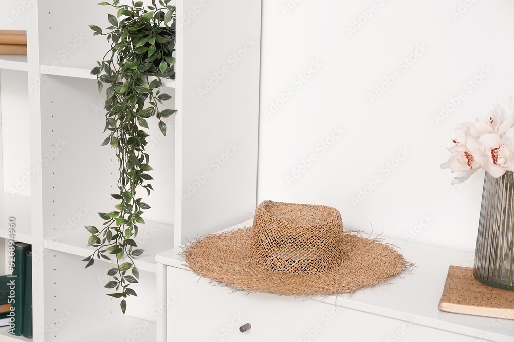 Stylish hat on chest of drawers near light wall