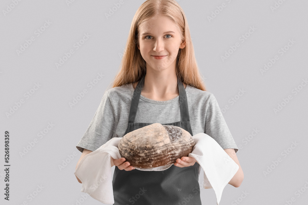 Young woman holding napkin with fresh bread on grey background