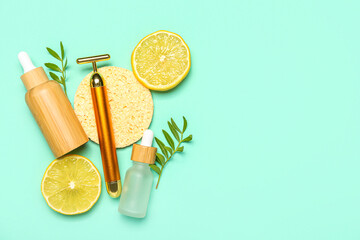 Facial massage tool with cosmetic dropper bottles, sponge, lemon slices and plant branches on green background