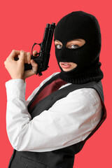 Wall Mural - Young woman in balaclava posing with gun on red background
