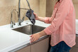 Woman housewife wiping kitchen faucet over sink with rag