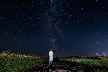 Wall Mural - lonely silhouette of a man against the background of the night sky with stars and the milky way.