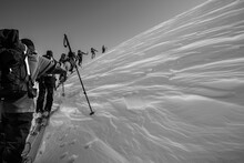 Group On Skis Climbing Snowy Mountain In A Row
