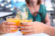 cold orange juice and wine glass with white wine in human hands clink glasses closeup photo