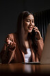 © wattana - Successful female entrepreneur talking on mobile phone sitting in office.