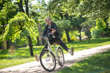 A Woman In Black Clothes Riding A Bike And Having Fun