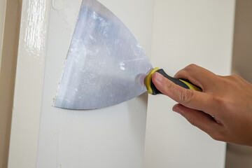 Man repairing crack white wall with spatula