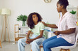 © Studio Romantic - Smiling dark-skinned teenage girl attends therapy session with young female child psychologist. Caring African American woman social worker works with girl to solve teenage problems.