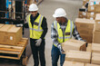 © Jacob Lund - Happy logistics workers loading cardboard boxes onto a pallet truck