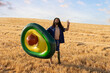 © VISTA by Westend61 - Smiling man with prosthetic leg holding avocado shaped inflatable ring gesturing peace sign at field