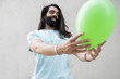 © VISTA by Westend61 - Smiling bearded man with long hair looking at green balloon
